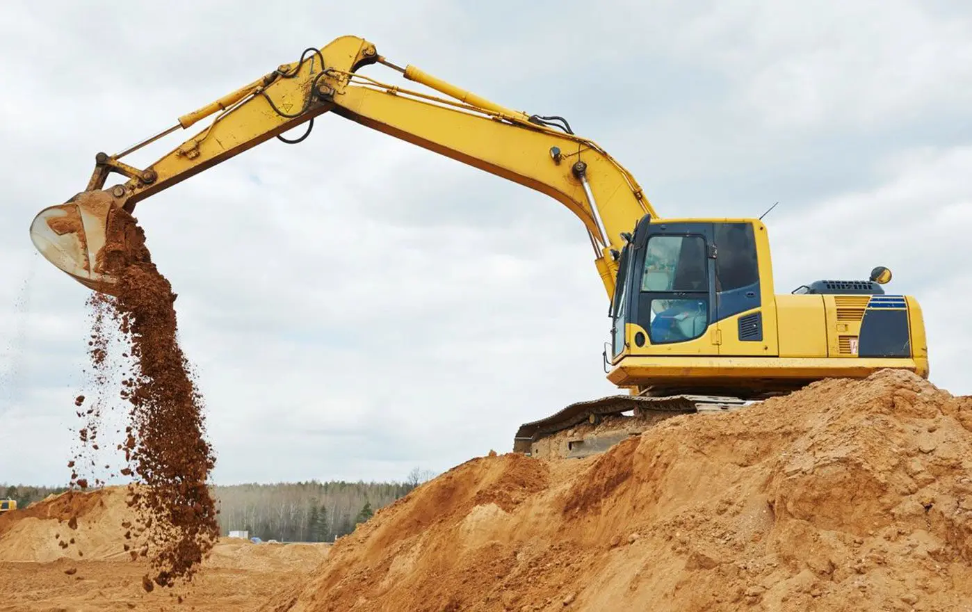 A yellow and black excavator on top of dirt.